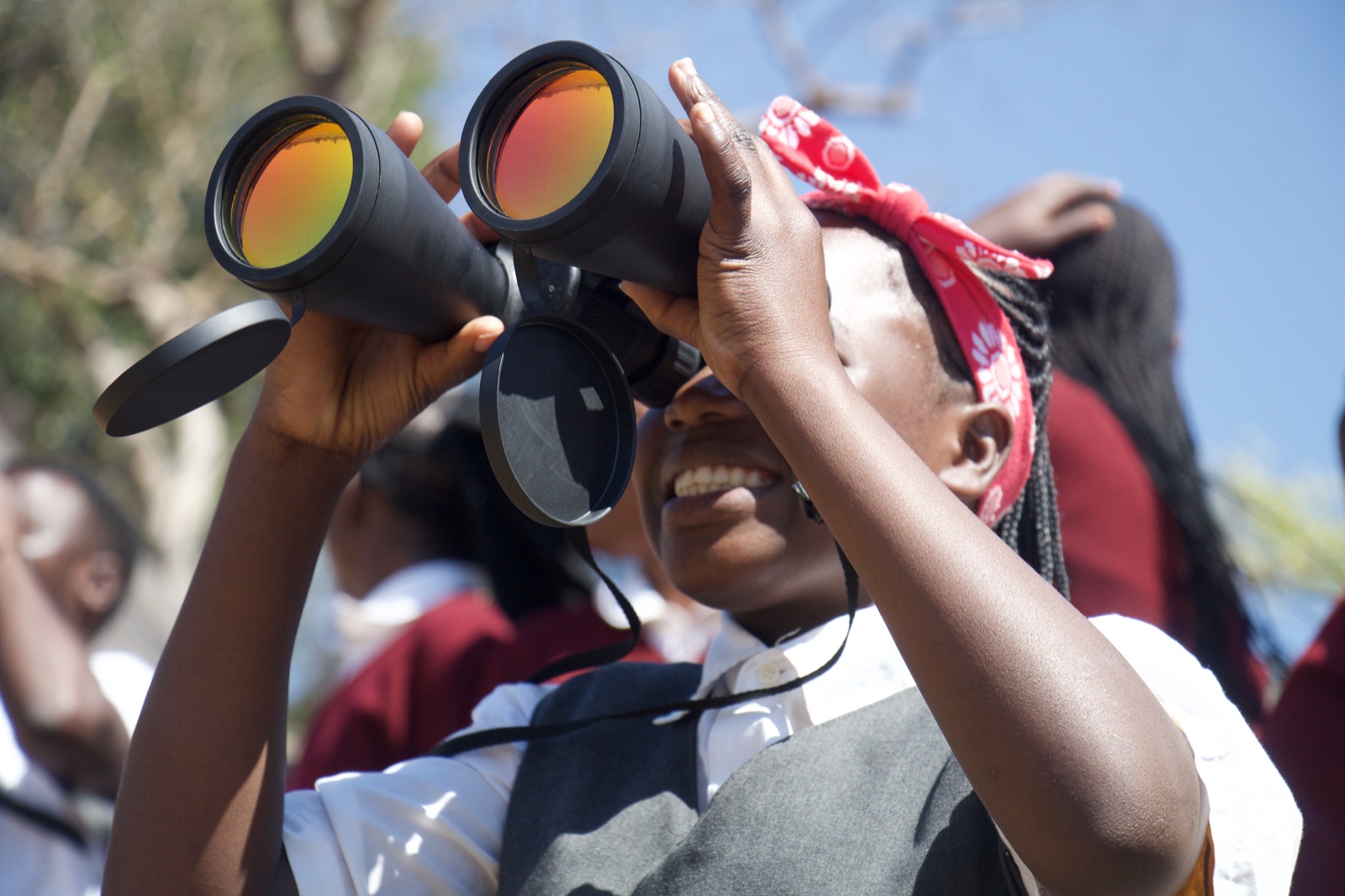 A student smiles while looking through binoculars during the Kasanka National Park trip